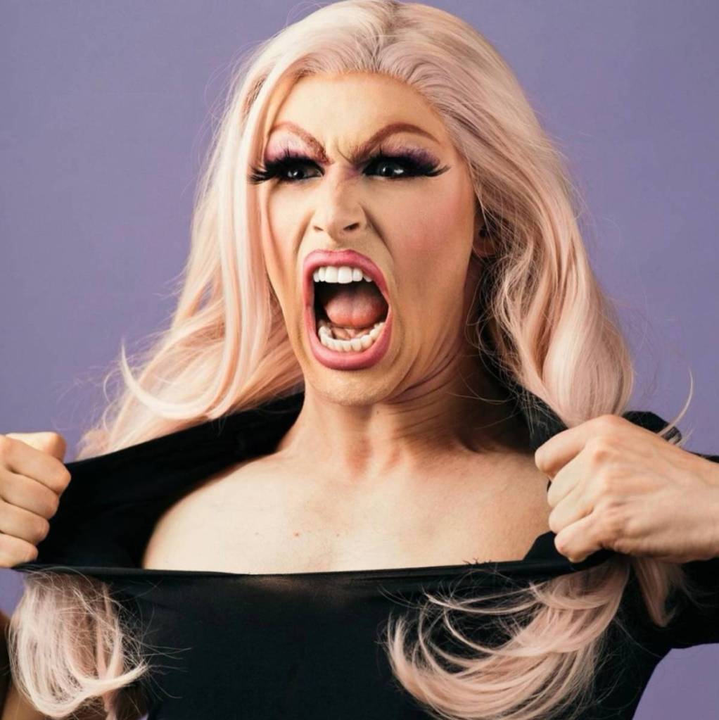Drag wrestler Alice Starr screams while pulling at the black collar of their shirt
