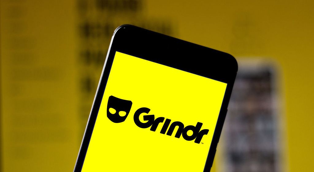 A phone showing a bright yellow screen and the word Grindr