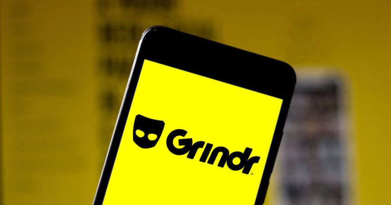 A phone showing a bright yellow screen and the word Grindr