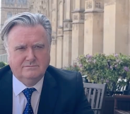 John Nicolson, a white man with grey hair, sitting outside the House of Commons