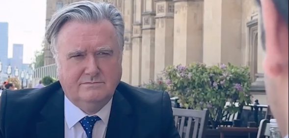 John Nicolson, a white man with grey hair, sitting outside the House of Commons