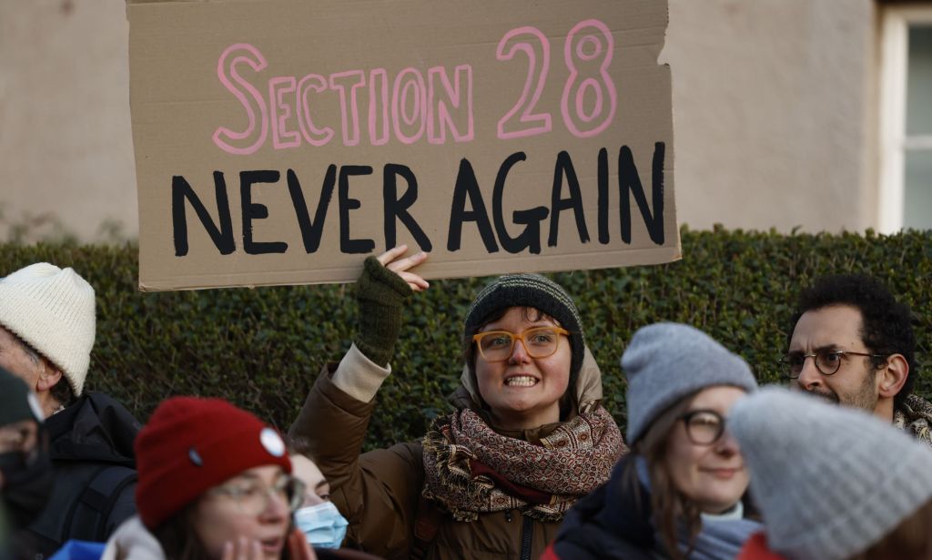 A person holds up a sign reading 'Section 28 never again' during a protest with LGBTQ+ and trans advocates in the UK