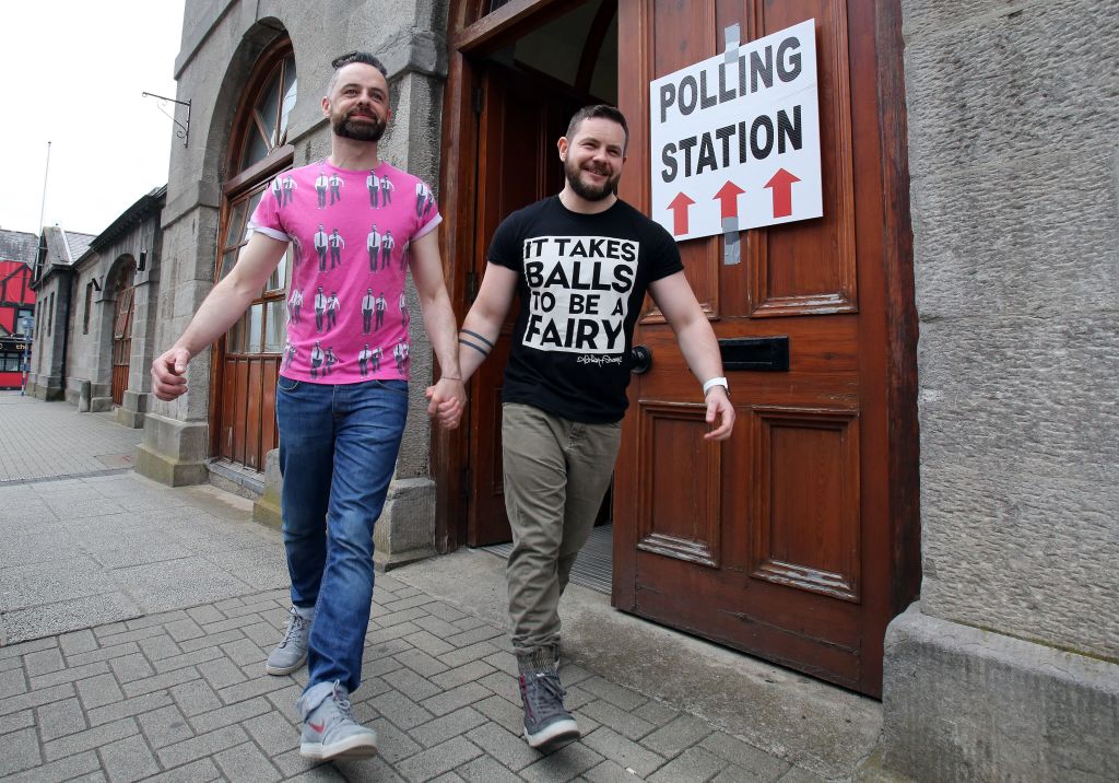 A gay couple pose holding hands as they walk out of a polling station after voting in Drogheda.