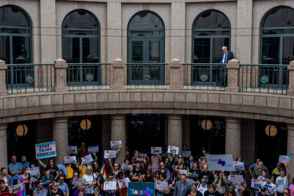 LGBTQ+ and trans rights advocates hold up signs in the Texas Capitol Building to protest against the wave of anti-LGBTQ+ bills in the state including a gender-affirming healthcare ban for trans youth