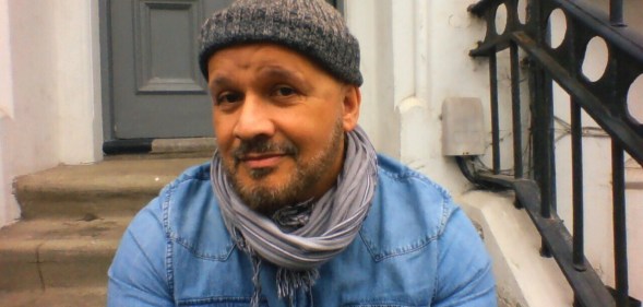 Paul, a mixed-race man with a greying beard, wearing a beanie hat, denim shirt and a scarf