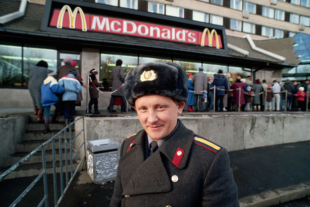 A Soviet policeman stands by a queue of people waiting to enter a newly opened McDonald's on Gorky Street in Moscow in 1990.  