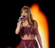 Taylor Swift wears a sparkly red two piece outfit as she sings into a microphone during a concert