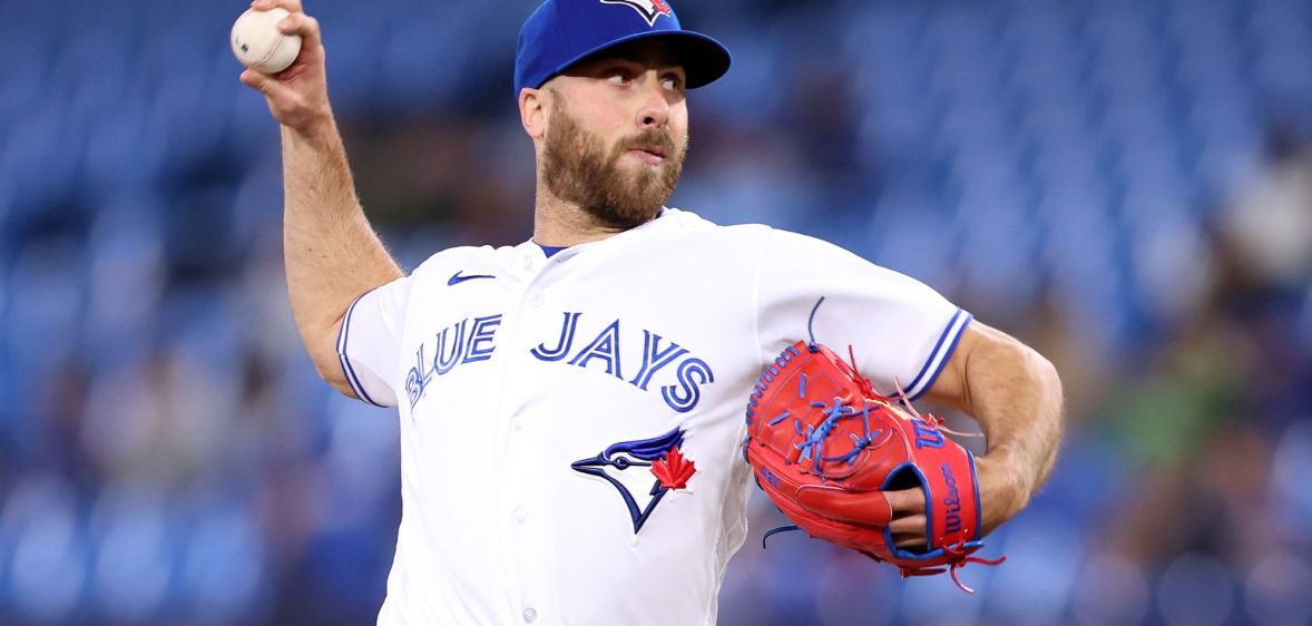 Toronto Blue Jays relief pitcher Anthony Bass wears a white uniform and blue baseball cap as he throws a baseball somewhere off screen