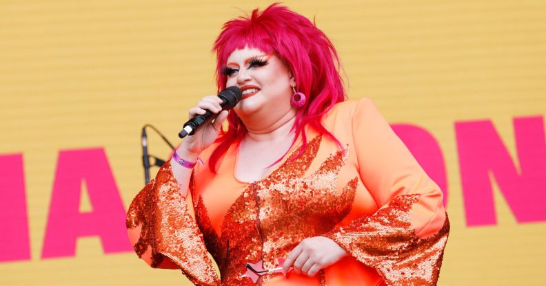 Drag Race star Victoria Scone in an orange outfit and red wig speaking to the crowd at Pride in London 2022.