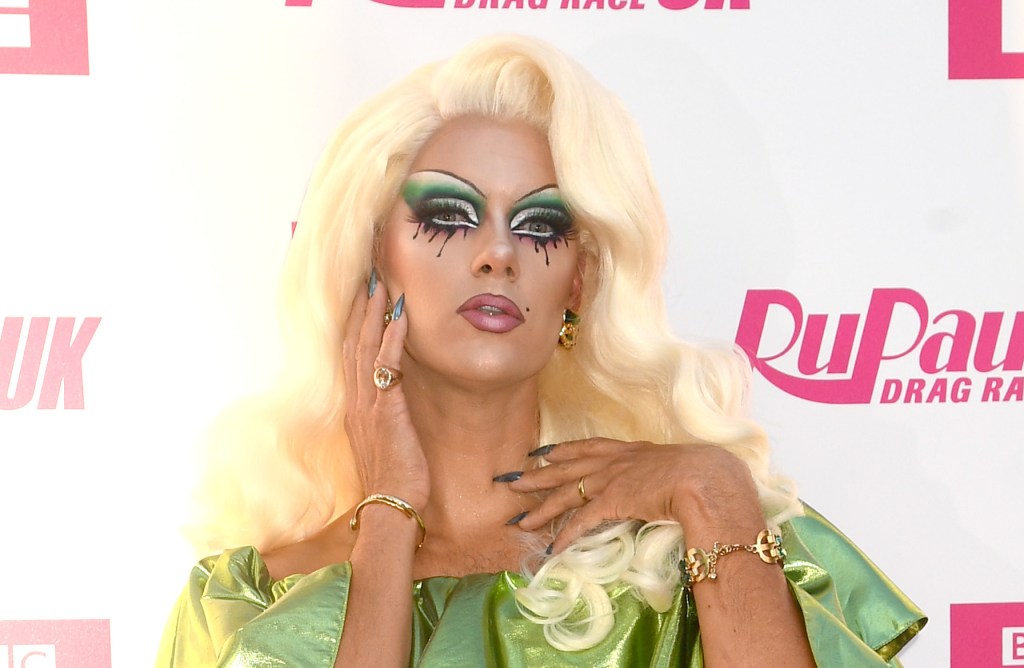 Drag Race UK contestant Crystal poses in a green dress against a white and pink background
