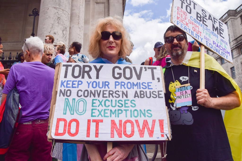 A protester holds a placard calling on the government to keep their conversion therapy ban promise during the rally outside St. Martin-in-the-Fields in Trafalgar Square.