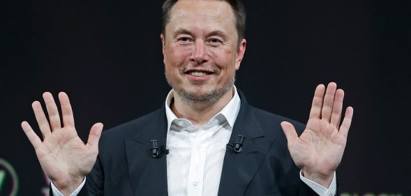 Owner of Twitter Elon Musk sits with his hands up