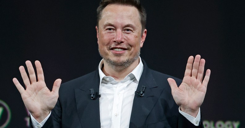 Owner of Twitter Elon Musk sits with his hands up