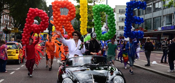 Revellers carry large multi-coloured balloons reading "PRIDE" at Belfast Pride in 2016