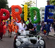 Revellers carry large multi-coloured balloons reading "PRIDE" at Belfast Pride in 2016