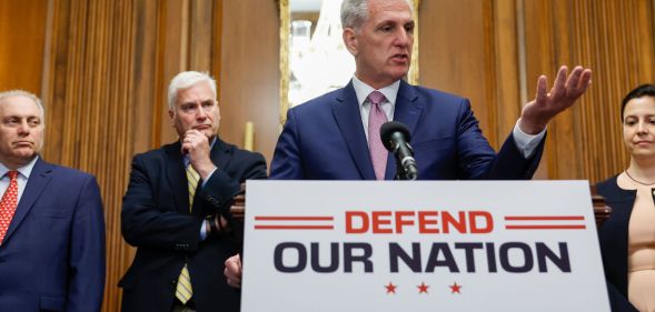 (L-R) Steve Scalise, Tom Emmer, Kevin McCarthy and Elise Stefanik stand around a press room discussing the recently passed National Defense bill, with McCarthy at a podium that says "defend our nation."