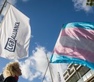 An LGB Alliance flag stands next to a trans flag, pointing towards the sky.