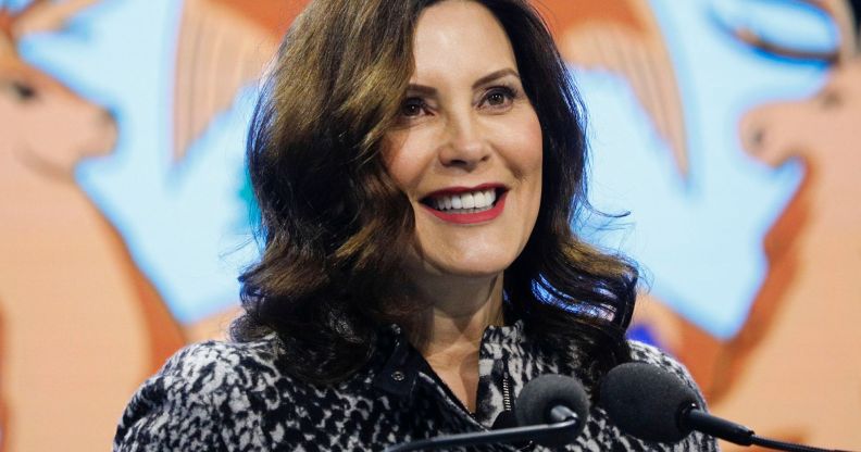 Gretchen Whitmer, Michigan Governor, smiles as she speaks into two microphones.