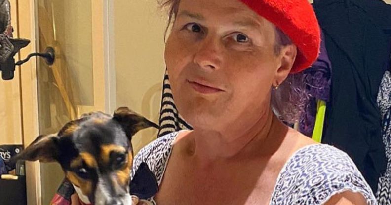 Sarah Jane Baker, in a red cap, holds her dog.