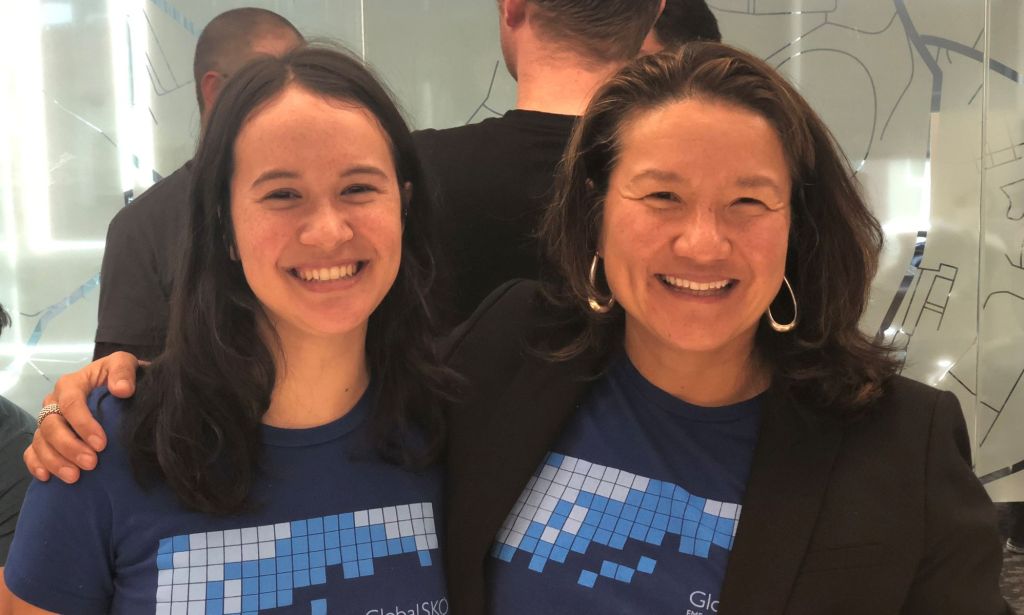 This is an image of two asian women. They are both wearing black and smiling. They are wearing the same t-shirt.