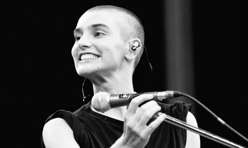 Sinéad O’Connor smiling on stage.