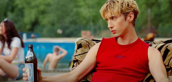 Troye sivan in a red vest and leather chaps in the new Rush music video.