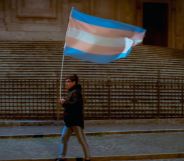 Person carries a large trans flag down the street