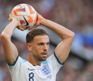 Footballer Jordan Henderson wears an England strip and gets ready to throw a football over his head during a match