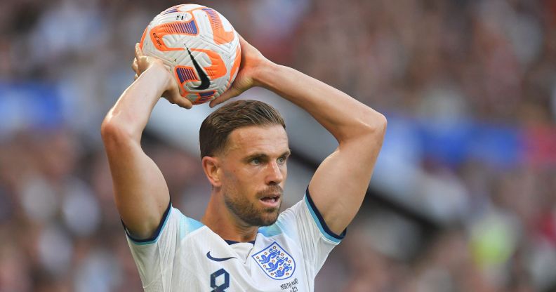 Footballer Jordan Henderson wears an England strip and gets ready to throw a football over his head during a match