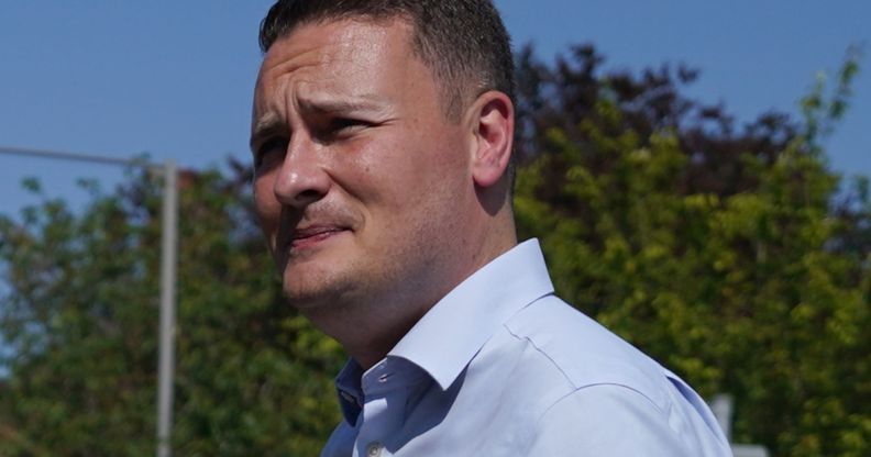 Wes Streeting wears a blue button shirt while walking around outside.