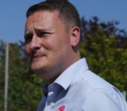 Wes Streeting wears a blue button shirt while walking around outside.