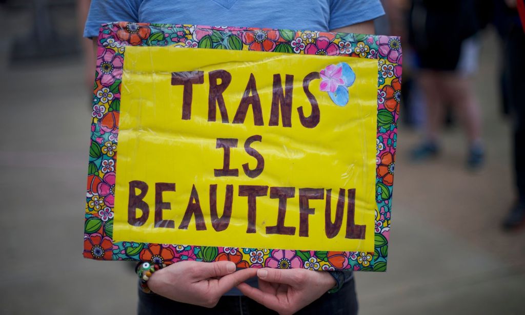 A person holds up a sign reading "trans is beautiful" during a demonstration in support of the trans community and lambasting anti-trans policies like bathroom bans, bans on gender-affirming healthcare and more