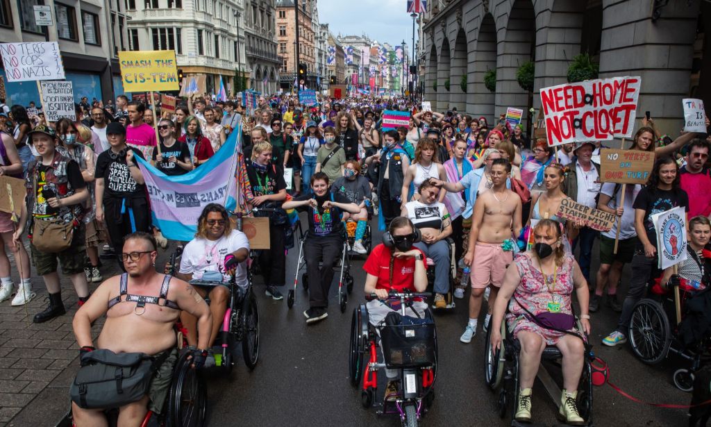 LGBTQ+ people and disabled folks using wheelchairs and other mobility devices march together during a Pride protest