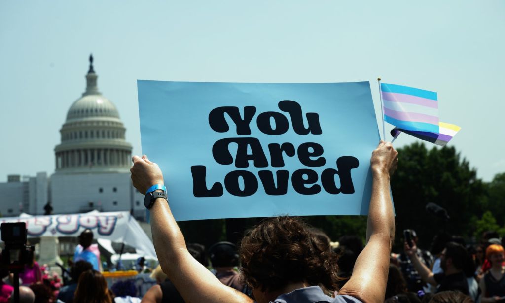 A person holds up a sign reading 'you are loved' during a demonstration in favour of the trans community amid legislative attacks on trans youth being able to access gender-affirming care