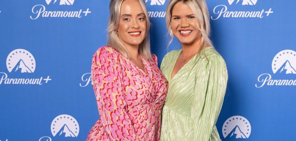 Lesbian couple Megan and Whitney Bacon-Evans, who are also campaigners for fertility equality, wear brightly colours dressed as they hold each other close and smile for the camera