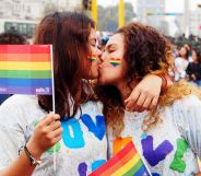 A couple kiss as they hold up rainbow LGBTQ+ Pride flags during a march in Peru where advocates call for same-sex marriage laws, for queer people to be protected from discrimination and more