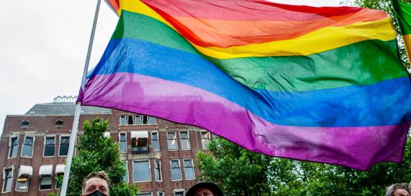 A person holds up a rainbow LGBTQ+ Pride flag