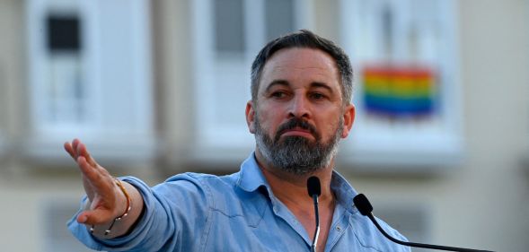 far-right party Vox leader Santiago Abascal holds his hand up during a political rally in Spain ahead of the general election as an LGBTQ+ flag can be seen in the background