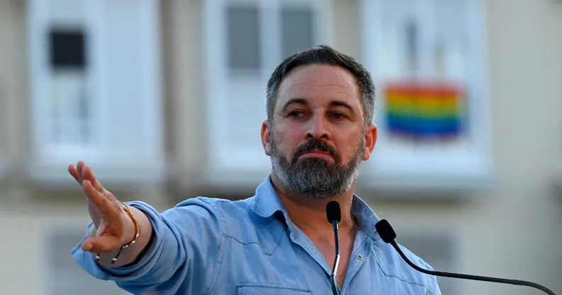 far-right party Vox leader Santiago Abascal holds his hand up during a political rally in Spain ahead of the general election as an LGBTQ+ flag can be seen in the background