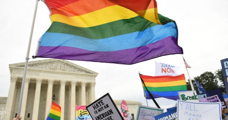 A LGBT pride flag waves in front of the Supreme Court