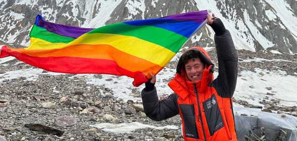 Aidan Hyman waves Pride flag near the summit of the K2 mountain