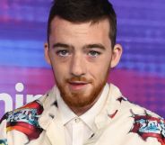 Angus Cloud, during a red carpet event, wears a white jacket with red graphics on it.