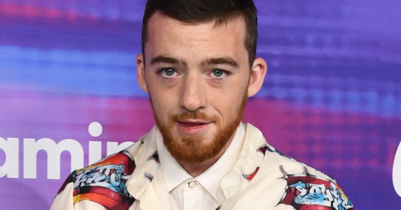 Angus Cloud, during a red carpet event, wears a white jacket with red graphics on it.