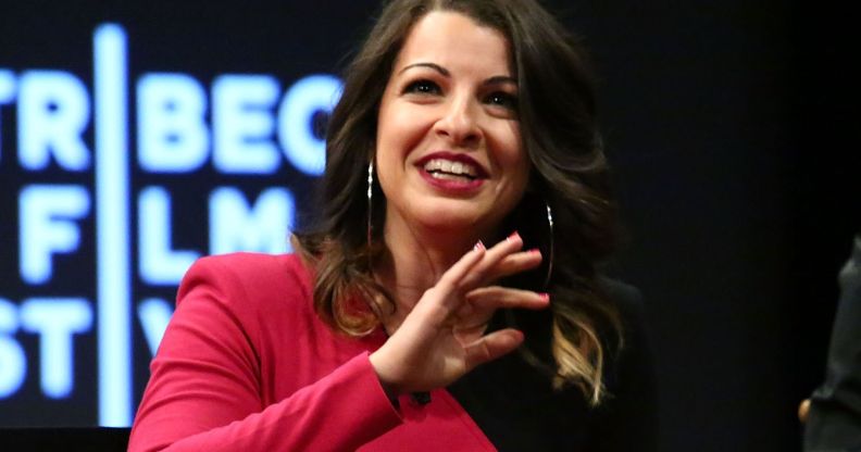 Anita Sarkeesian, in a black and pink dress, speaks at an event.