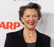 Annette Bening in a black blazer and top smiling at the camera while on the red carpet.