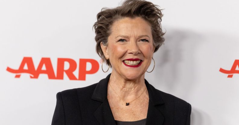 Annette Bening in a black blazer and top smiling at the camera while on the red carpet.