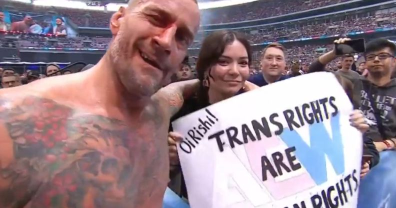 CM Punk with a fan holding a sign that reads "Oi Rishi! Trans rights are human rights."