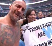 CM Punk with a fan holding a sign that reads "Oi Rishi! Trans rights are human rights."