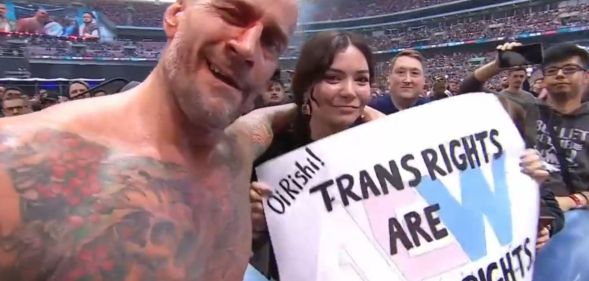 CM Punk with a fan holding a sign that reads "Oi Rishi! Trans rights are human rights."