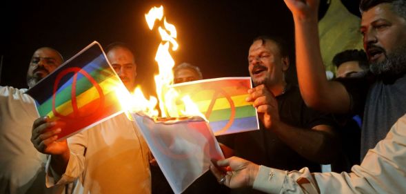 Homophobic protestors in Iraq burn pictures of the LGBTQ+ Pride flag.